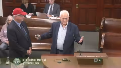 Rochester Mayor speaks as Dover Mayor wears a Rochester football hat after losing a bet.